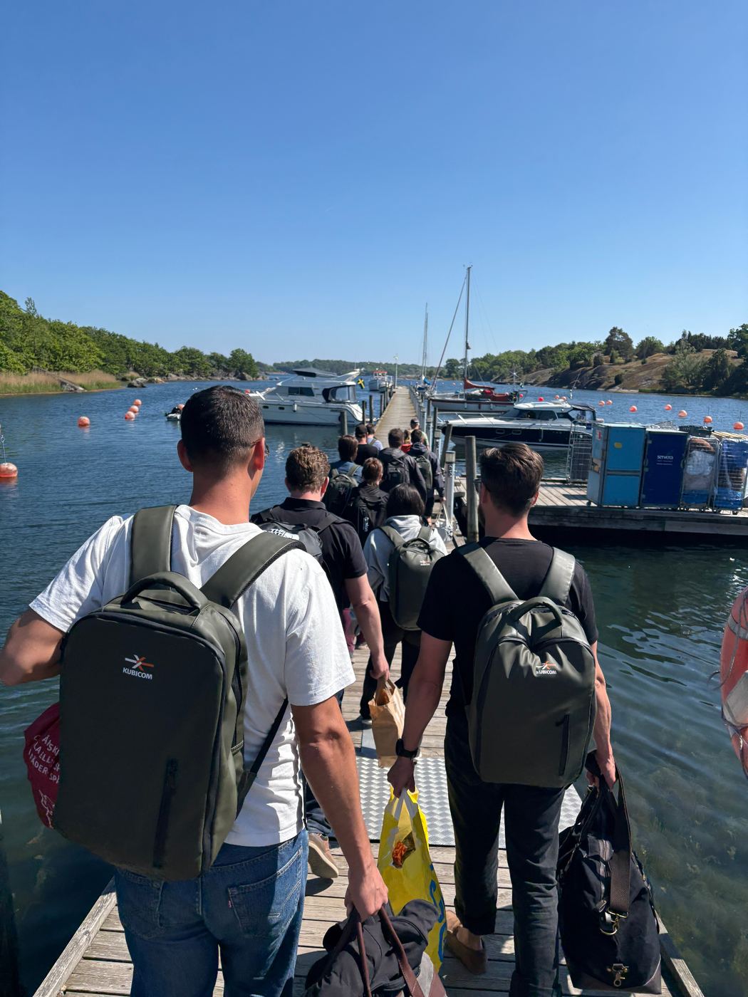 Kubicom-teamet med ryggsäckar på väg ut till båt i skärgården