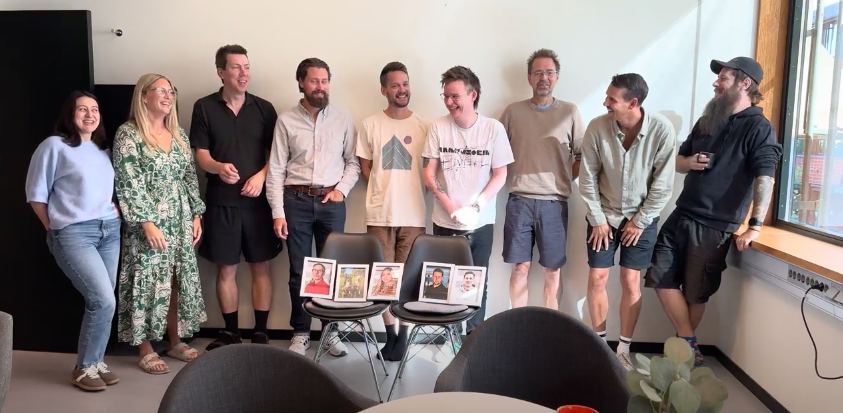 Kubicom-teamet samlat med inramade kollegaporträtt