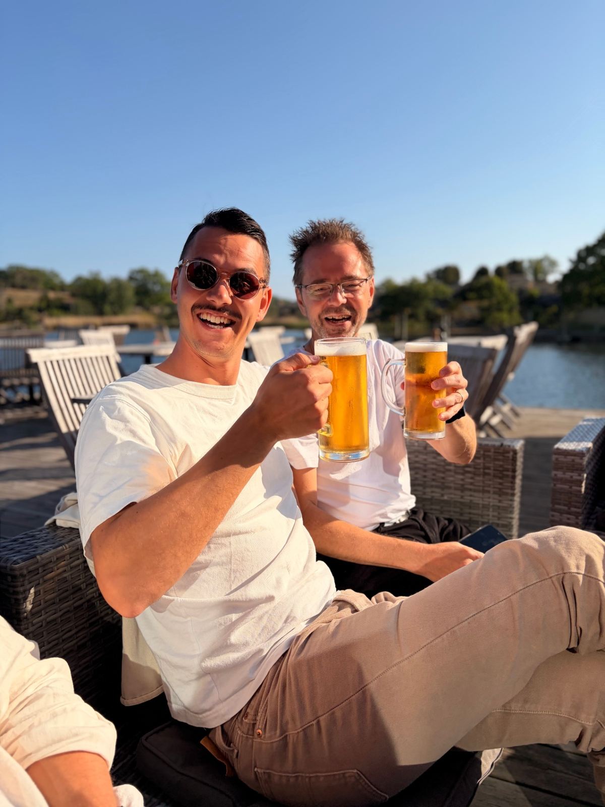 Två kollegor skålar på en sommarkväll vid vattnet